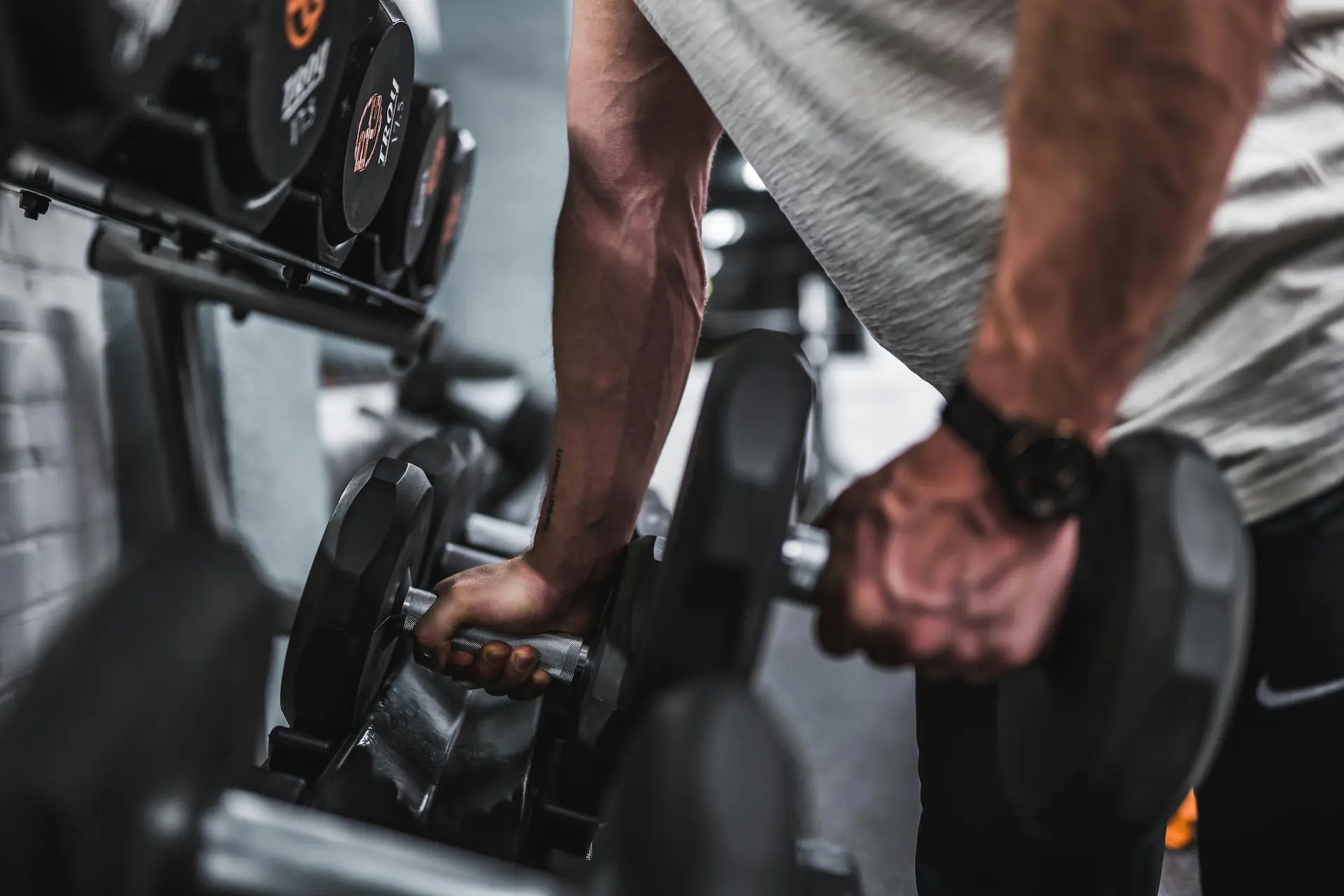 Male lifting dumbbells off of rack